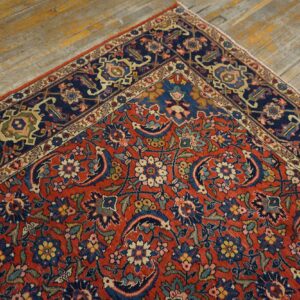 Red and navy traditional rug featuring an intricate floral pattern and detailed border on wood plank flooring.