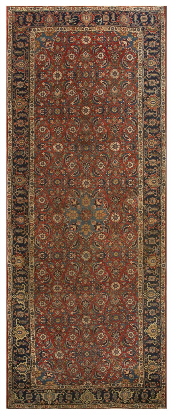 Rust-red runner rug with an all-over complex floral pattern and dark navy blue outer and inner borders.