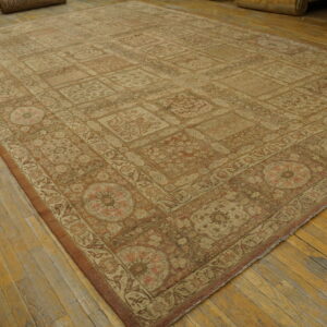 Large faded rug with repeating beige and rust floral motifs covers a distressed wood floor.