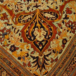 Intricate traditional rug pattern featuring large rust and dark blue floral motifs on a light sage background.