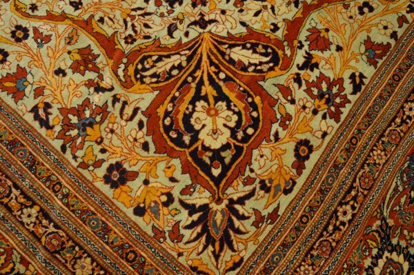 Intricate traditional rug pattern featuring large rust and dark blue floral motifs on a light sage background.