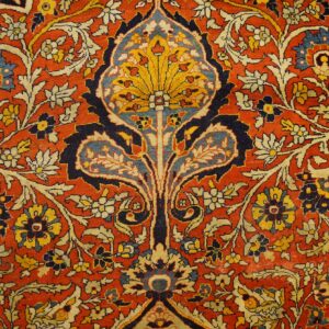 Rust red rug featuring a central stylized yellow and blue motif surrounded by dense florals.