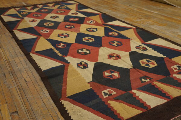 Geometric flatweave runner rug in navy, red, cream, and gold on rustic wooden plank flooring.