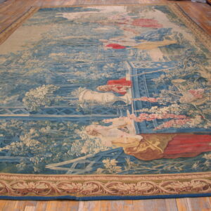 Detailed blue and beige tapestry rug depicts a pastoral garden scene with figures on wood plank floor.