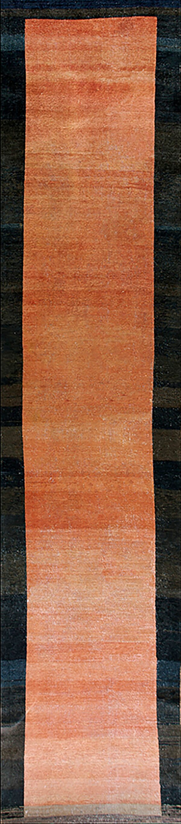 Long rust-colored hallway runner rug featuring subtle horizontal striations laid upon dark, striped flooring.