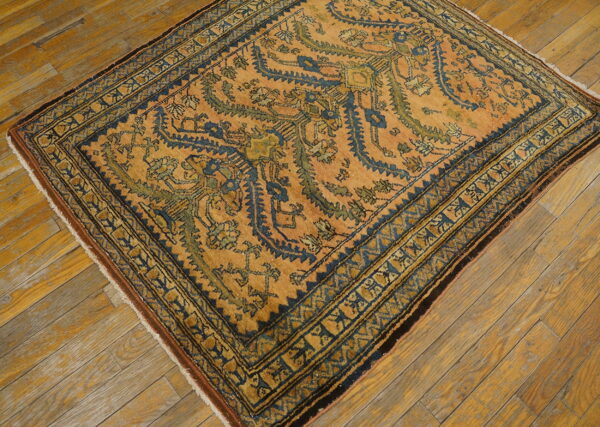 Rust and indigo rug with geometric motifs and borders rests on natural, warm-toned wood flooring.