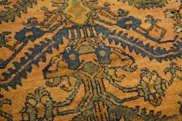 Close-up of a rug showing a traditional pattern in rust orange, deep indigo, and olive green colors.