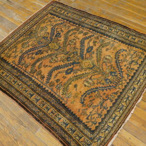 Square rug in warm orange, navy, and moss green, featuring traditional stylized patterns on wood planks.