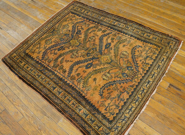 Square rug in warm orange, navy, and moss green, featuring traditional stylized patterns on wood planks.