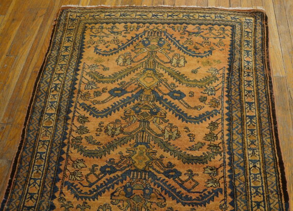 Saffron-orange rug featuring a dark blue stylized tree design and detailed borders on hardwood flooring.