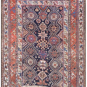 A dark blue geometric rug features repeating medallions bordered by complex terracotta and cream designs.
