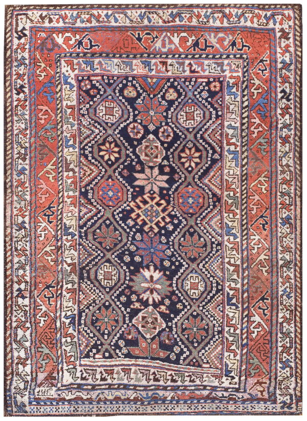 A dark blue geometric rug features repeating medallions bordered by complex terracotta and cream designs.