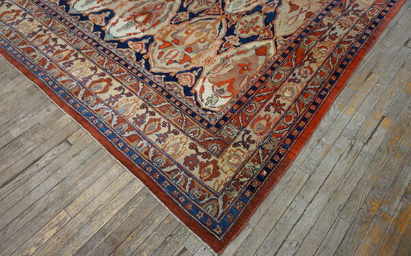 Ornate navy, rust, and cream patterned rug corner resting on weathered gray hardwood planks.