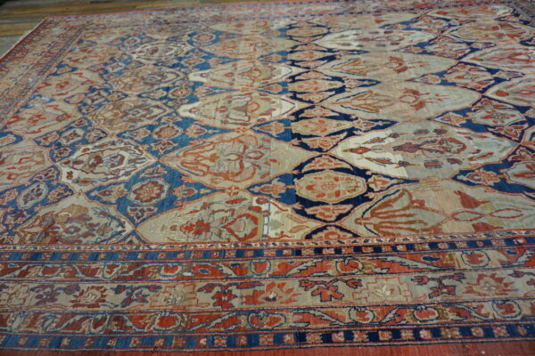 Beige rug with a distressed blue and rust ogee pattern displayed on a rustic wood floor.