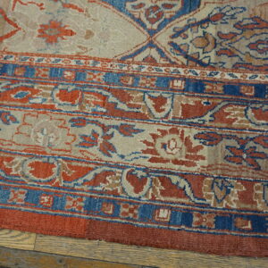 Muted beige, terracotta, and deep blue traditional rug border detailing rests on light hardwood flooring.