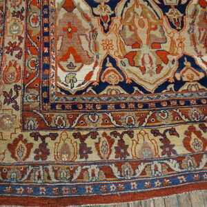Ornate navy, rust, and beige traditional patterned rug detail rests on rustic wood planks.