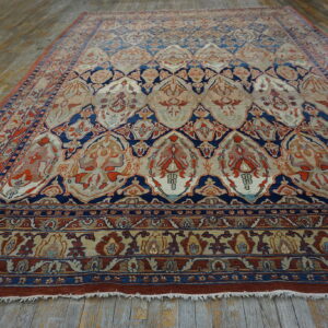 Ornate navy blue, rust, and beige lattice pattern rug on weathered hardwood plank flooring.