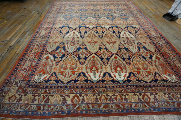 Ornate navy, rust, and beige patterned rug covers aged, narrow wood plank flooring.