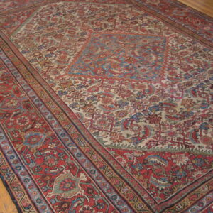 Low-pile traditional red and ivory rug with blue floral patterns resting on light hardwood flooring.