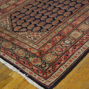 Traditional rug with a navy field of red boteh motifs, framed by complex red and olive green borders.