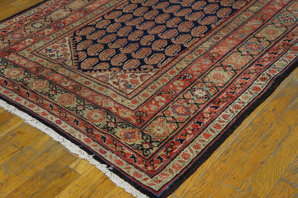 Traditional rug with a navy field of red boteh motifs, framed by complex red and olive green borders.