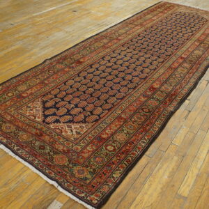 Navy and red patterned runner rug with intricate borders rests on light, wide plank wooden flooring.