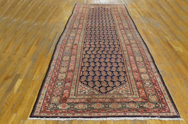 Runner rug with a dark blue central field and red repeating motifs, featuring intricate borders on wood planks.