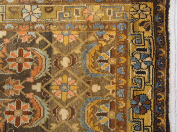 Traditional rug detail showing dark brown, gold, blue, and peach floral motifs within complex geometric borders.