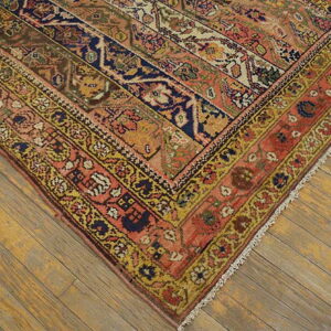 A patterned rug with alternating coral, navy, and gold striped panels rests on rustic wood floors.