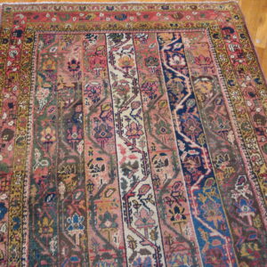 Multi-paneled rug featuring pink, navy, yellow, and red colors with dense floral patterns on light wood flooring.