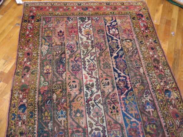 Multi-paneled rug featuring pink, navy, yellow, and red colors with dense floral patterns on light wood flooring.