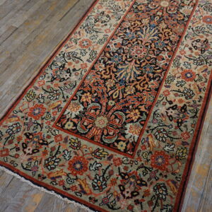 Low-pile runner with intricate red, blue, and sage floral patterns on rustic, gray wooden floorboards.