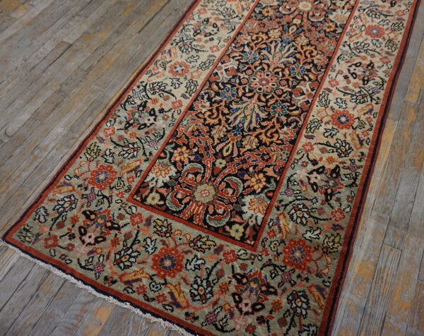 Low-pile runner with intricate red, blue, and sage floral patterns on rustic, gray wooden floorboards.