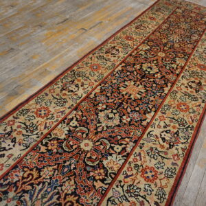 Ornate black, red, and beige runner rug on distressed gray wood plank flooring.