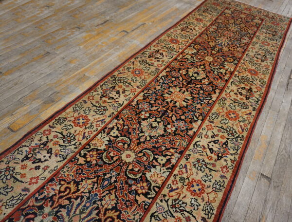Ornate black, red, and beige runner rug on distressed gray wood plank flooring.