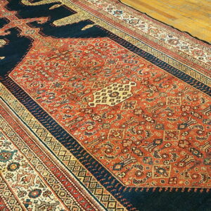 Long runner rug featuring a detailed terracotta field and deep navy spandrels on light wood flooring.