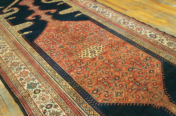 Long runner rug featuring a detailed terracotta field and deep navy spandrels on light wood flooring.