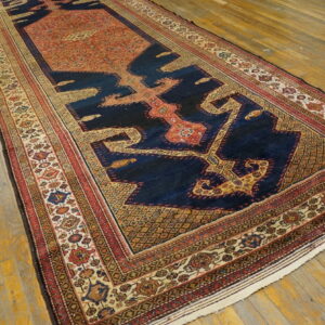 Long runner rug with a navy, rust, and beige geometric pattern rests on wide plank wood flooring.