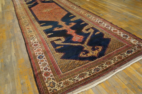Long runner rug with a navy, rust, and beige geometric pattern rests on wide plank wood flooring.