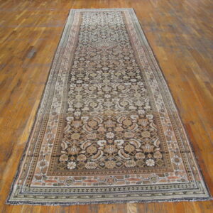 Ornate runner rug with detailed beige and dark brown patterns laid on a polished plank wood floor.