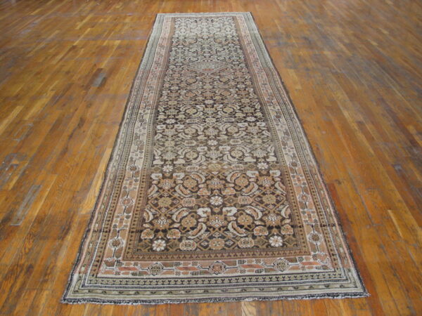 Ornate runner rug with detailed beige and dark brown patterns laid on a polished plank wood floor.