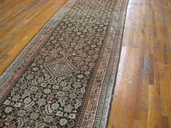 Dark brown traditional runner with beige, tan, and rust accents, centered on distressed wood floorboards.