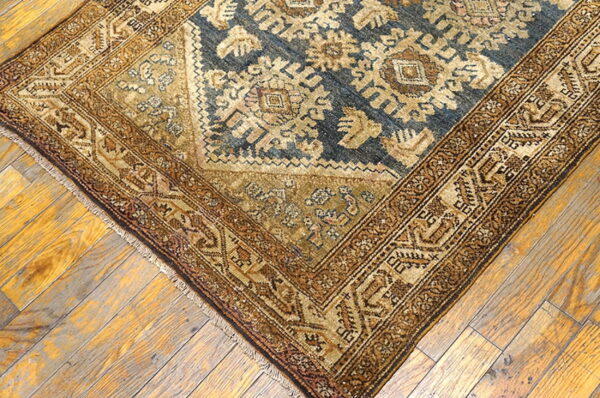 Close-up of a blue and tan geometric rug on worn, diagonally laid hardwood planks.