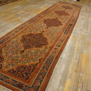 Traditional runner rug in cream, red, and blue with three dark medallions on distressed wood floorboards.