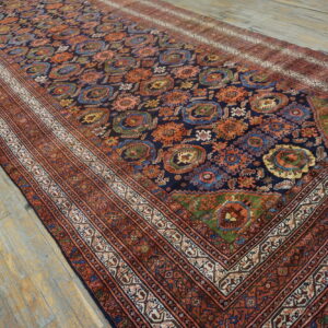 Long navy rug featuring complex orange and blue tribal motifs, framed by rust borders, on distressed wood.