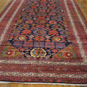 A long, dark blue rug with intricate red and multicolor medallion patterns is laid on wood plank floors.
