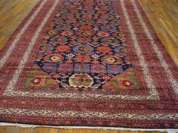 A long, dark blue rug with intricate red and multicolor medallion patterns is laid on wood plank floors.