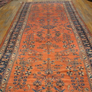 A narrow terracotta runner featuring blue geometric and floral designs resting on a wooden floor.