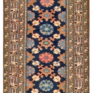 Navy blue runner rug with repeating floral medallions in pink and teal, surrounded by complex geometric borders.