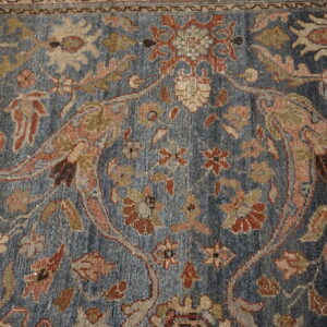Intricate blue rug features a traditional floral design highlighted with rust, beige, and muted olive accents.